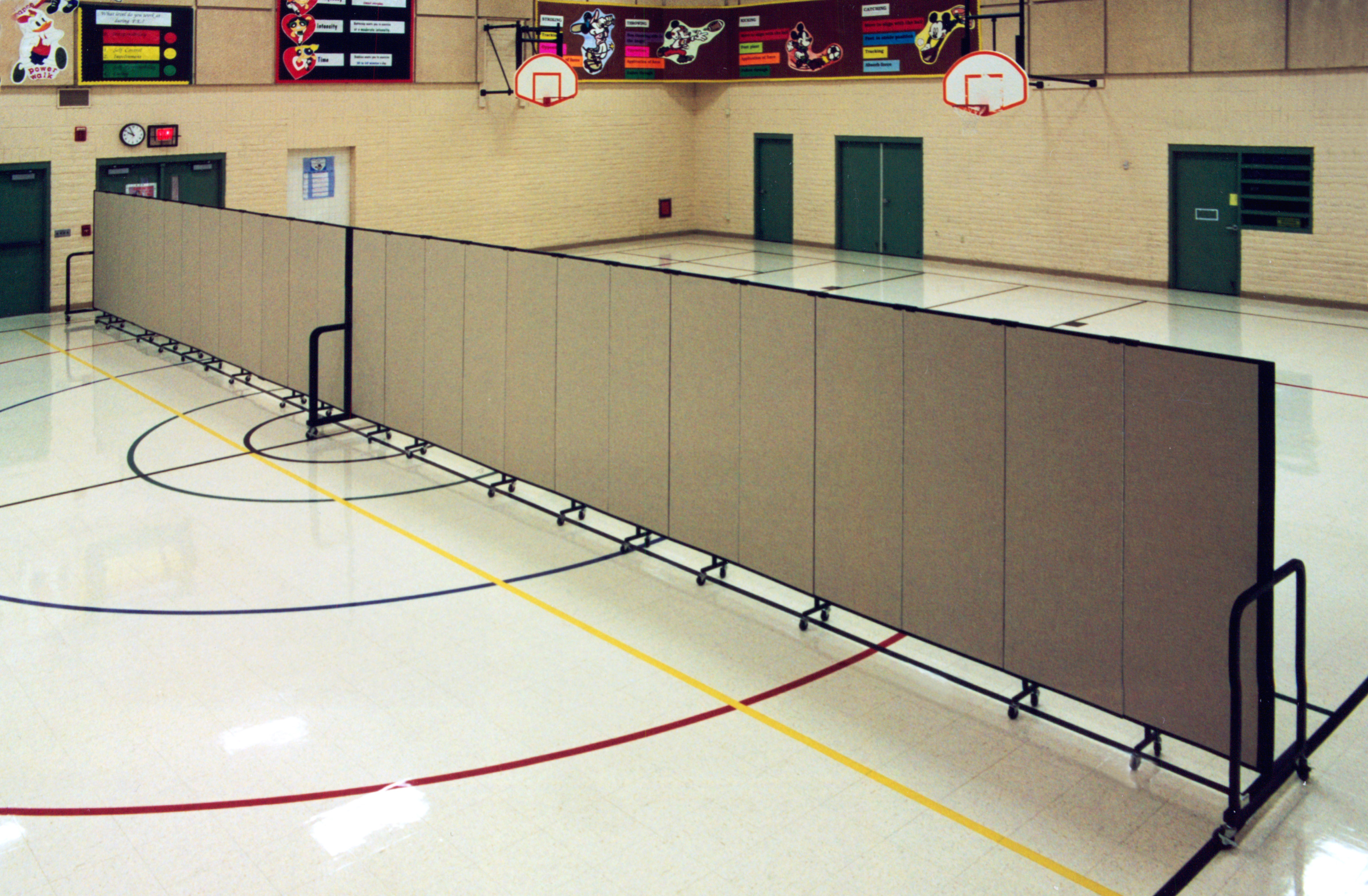 Too hot for outdoor PE class? Screenflex accordion walls are used to divide this gymnatorium. Half is used for PE and half for lunch.