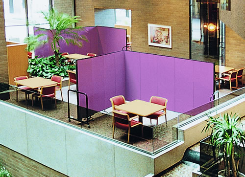 Purple room dividers in an L-shape around a set of chairs and a table in a hotel lobby