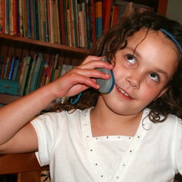 An elementary school girl talks on a cell phone