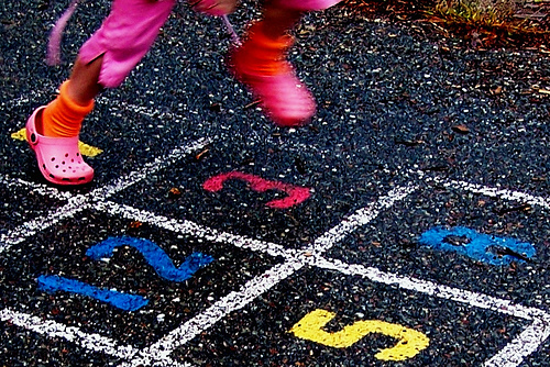 The feet of a young girl playing hopscotch