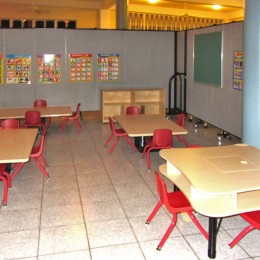 4 short table and chairs are arranged on a tile floor in a preschool room