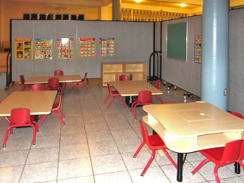 4 short table and chairs are arranged on a tile floor in a preschool room