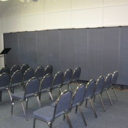 Four rows of stackable chairs towards a podium