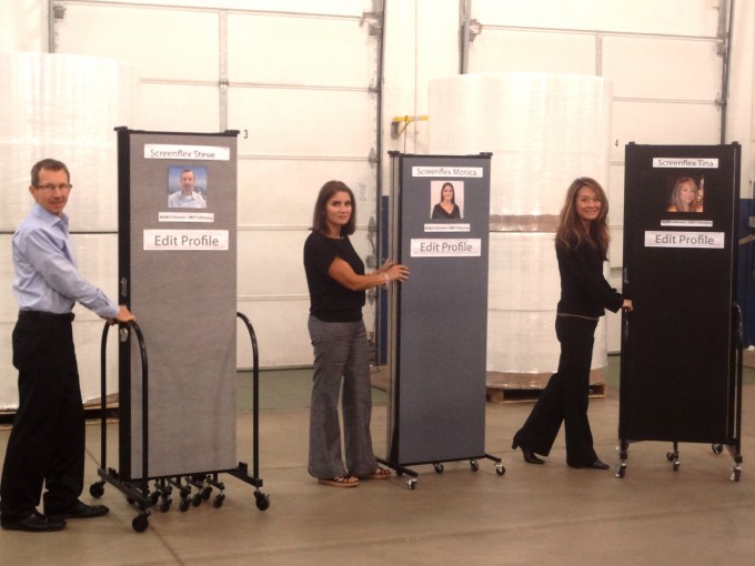 A man and two women each stand next to a Screenflex Portable Room Divider