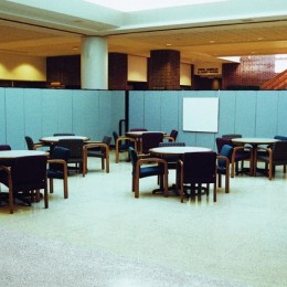 Screenflex Room Dividers are arranged in an L-shape to create a designated meeting area in a library lobby