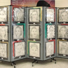 Student self portraits hang on a Screenflex Portable Partition