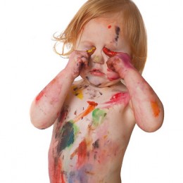 Toddler in a diaper with finger paint on its chest and hands