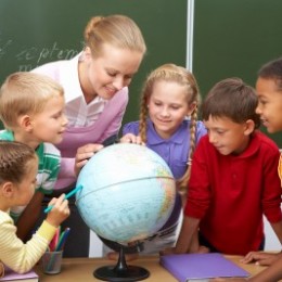 A teacher and students look at a globe