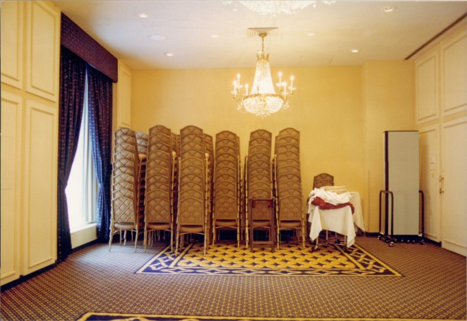 12 tall stacks of banquet chairs in the rear of a banquet room