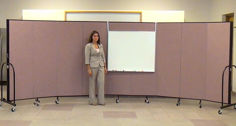 A teacher stands beside a portable dry erase board hung on a Screenflex Room Divider