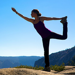 A female doing a yoga pose on top of a mountain