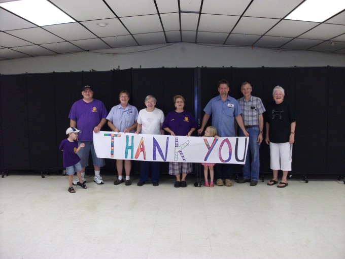 Happy customers hold a thank you sign up for their Screenflex room dividers