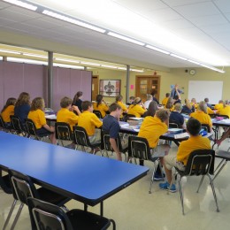 Students sit at tables listening to a teacher on one side a room divided by a Screenflex Room Divider