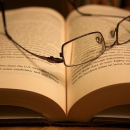 Mens glasses lay across an open book