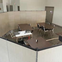 Screenflex Room Dividers are arranged around a group of 4 tables and a projector to create a conference room within a large open meeting area.