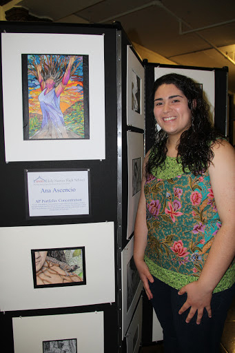 Female stands next to her drawing displayed on Screenflex Room Divider at a student art gallery.