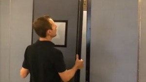 A man attaches an optional door onto a Screenflex Room Divider Unit.