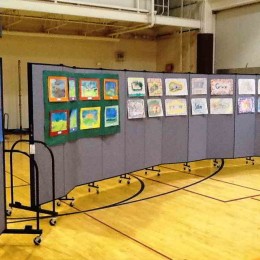 Student artwork displayed on two 11 panel Screenflex room dividers in a gymnasium