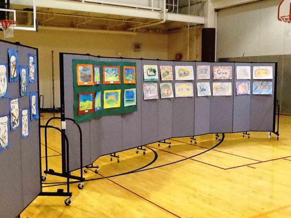 Student artwork displayed on two 11 panel Screenflex room dividers in a gymnasium